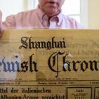 A man holding up a copy of the Jewish Chronicle newspaper. 